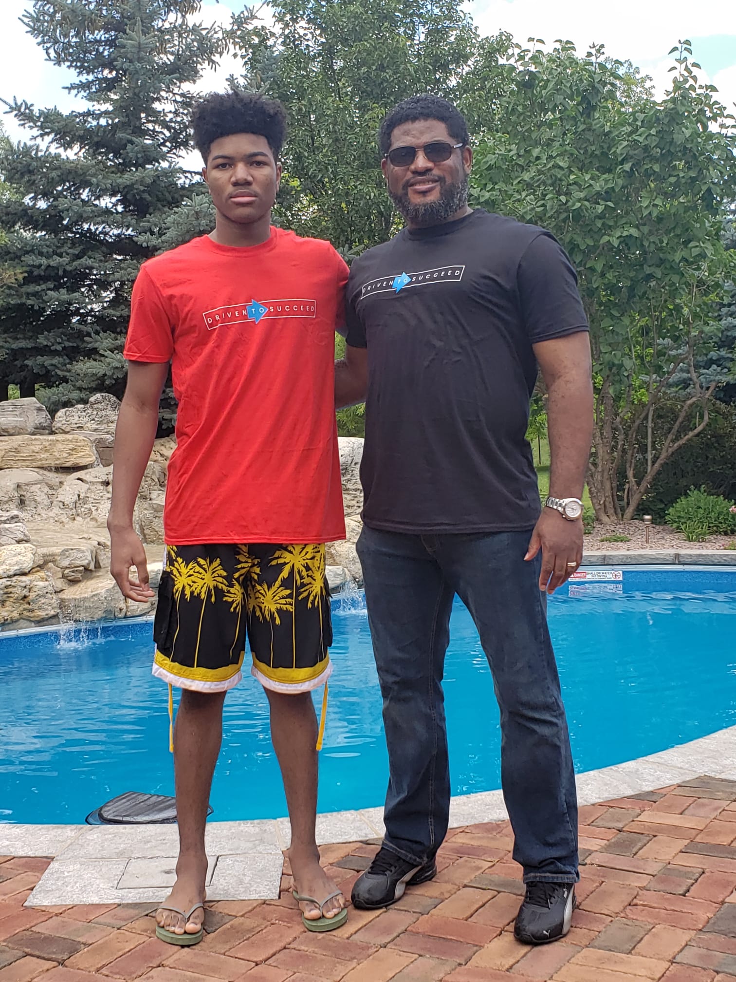 two men standing beside a swimming pool